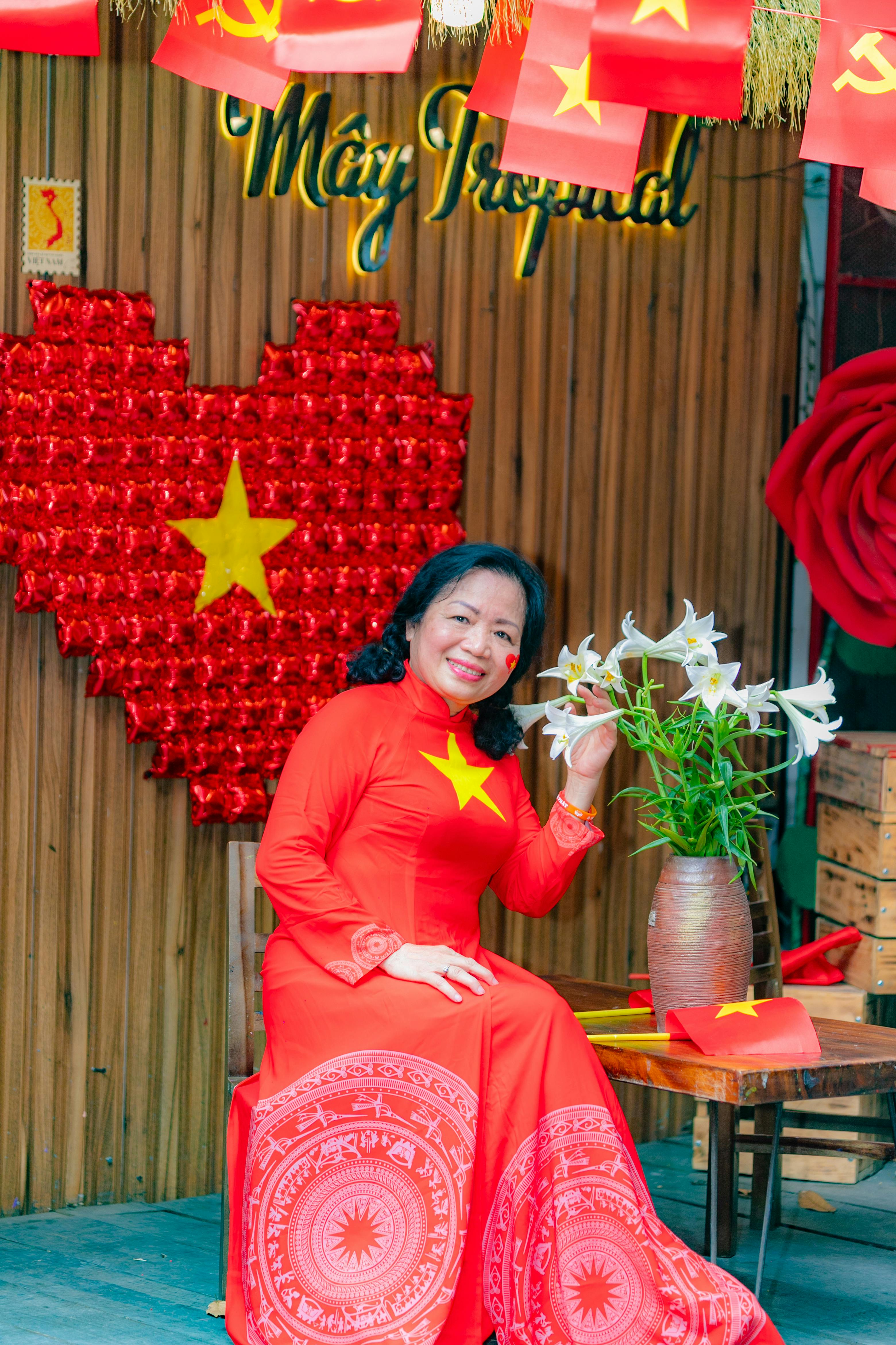 Smiling woman in red áo dài amidst Vietnam flag decor in Hải Phòng.