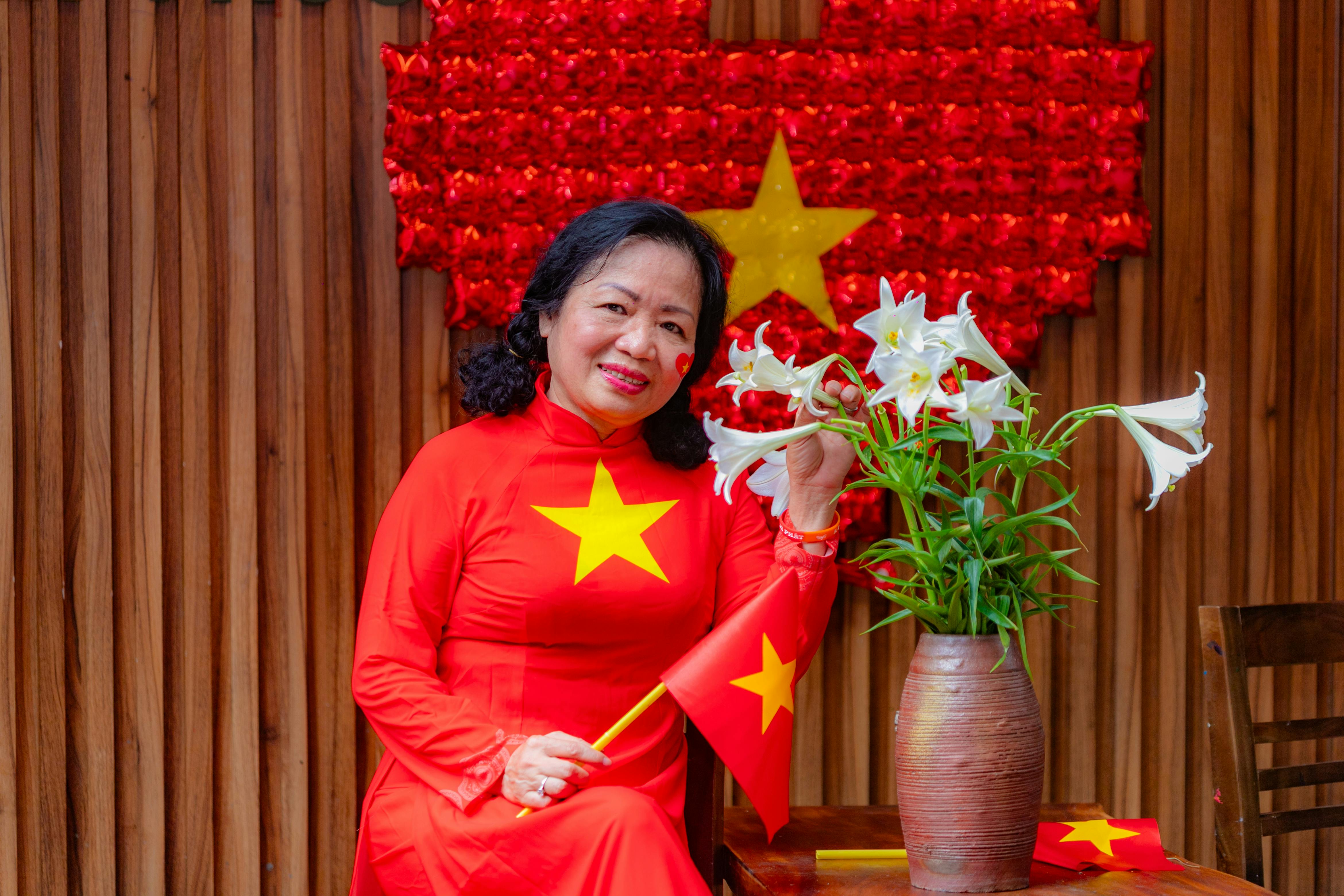 Vietnamese woman in red áo dài with national flag celebrating in Hải Phòng.