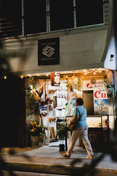 Woman walking past a charming shop in Merida, Yucatan at night.
