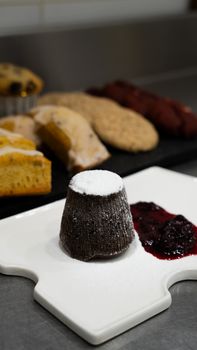 Assorted desserts including chocolate lava cake and fruit compote, presented on a white plate in a kitchen setting.