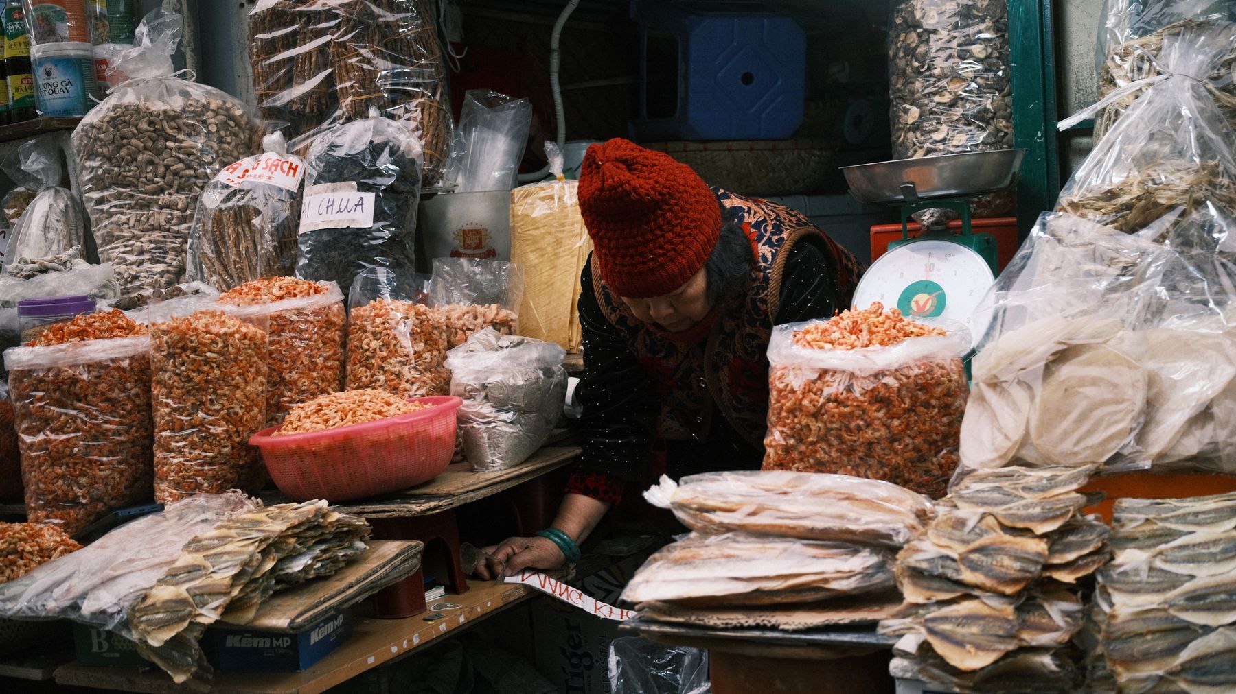 Una bancarella di un mercato asiatico piena di vari prodotti essiccati, che mostra una vivace atmosfera di shopping.
