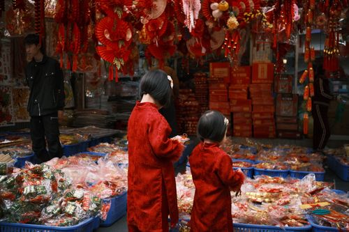 Free Children shopping in a vibrant Chinese market during New Year celebrations with festive red decorations. Stock Photo
