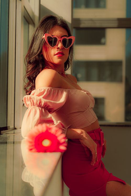 Free Confident woman in pink sunglasses poses by a sunny window. Stock Photo