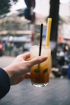 Close-up of a hand with a refreshing iced drink, capturing urban street life.