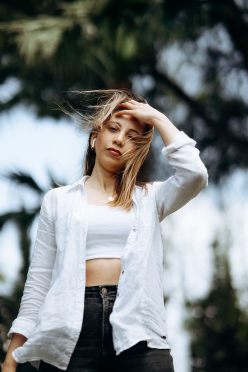 Free Portrait of a young woman outdoors in a white blouse with flowing hair. Stock Photo