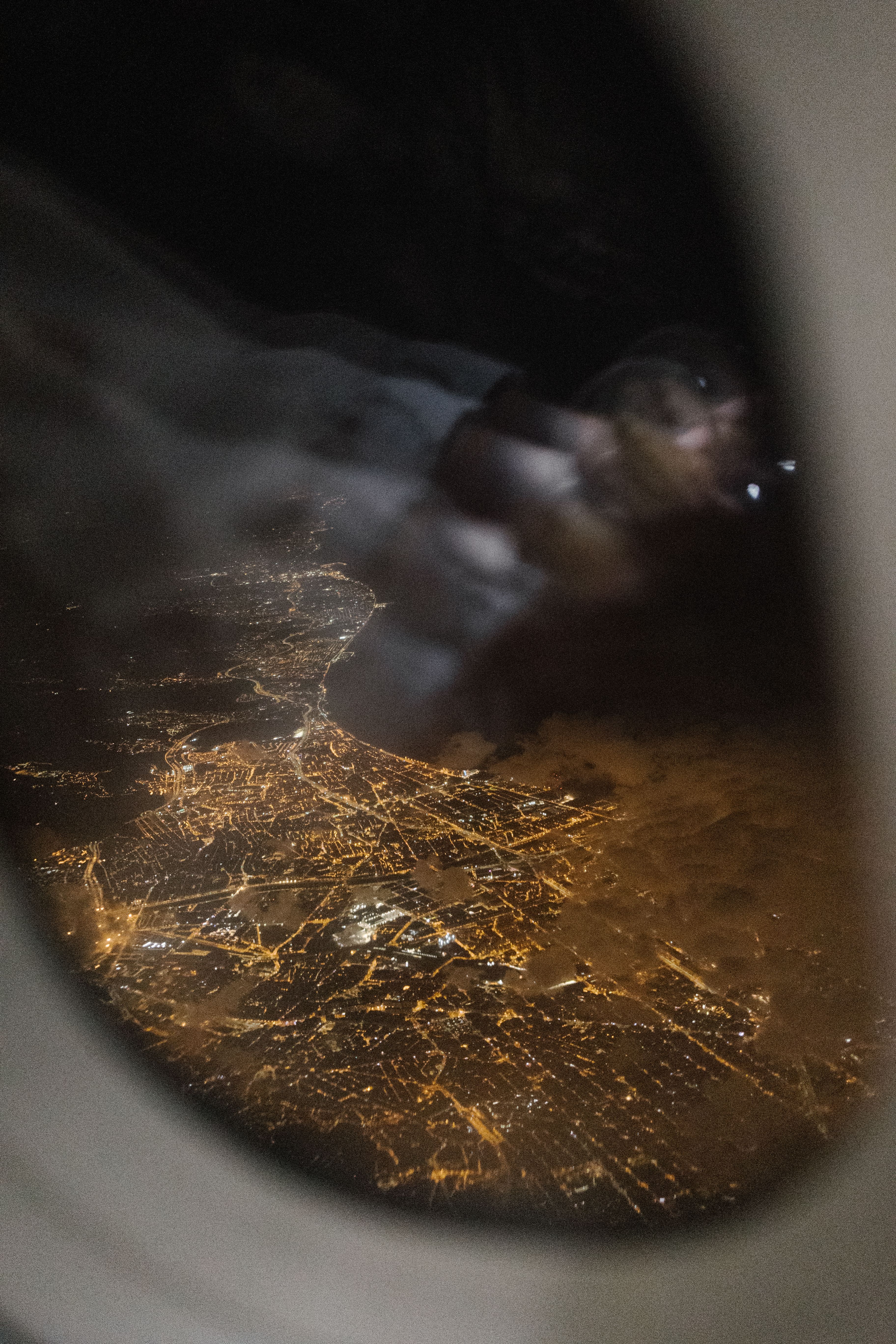 Stunning aerial night view of illuminated city through airplane window.