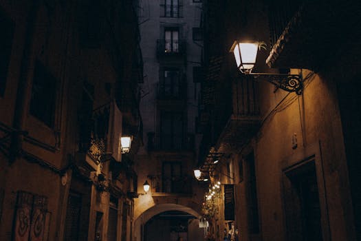 Dimly lit narrow alleyway at night, featuring vintage street lamps casting a warm glow.