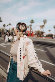 Woman in trendy outfit enjoying a sunny day in the city with a backdrop of palm trees.