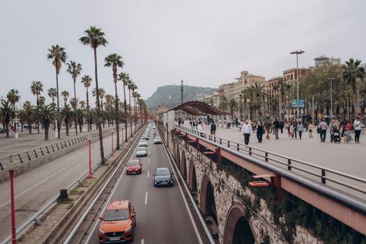 Street view in Barcelona featuring traffic, palm trees, and pedestrian activity.