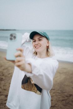 Smiling woman capturing a selfie with her smartphone on a beach in Barcelona, Spain.