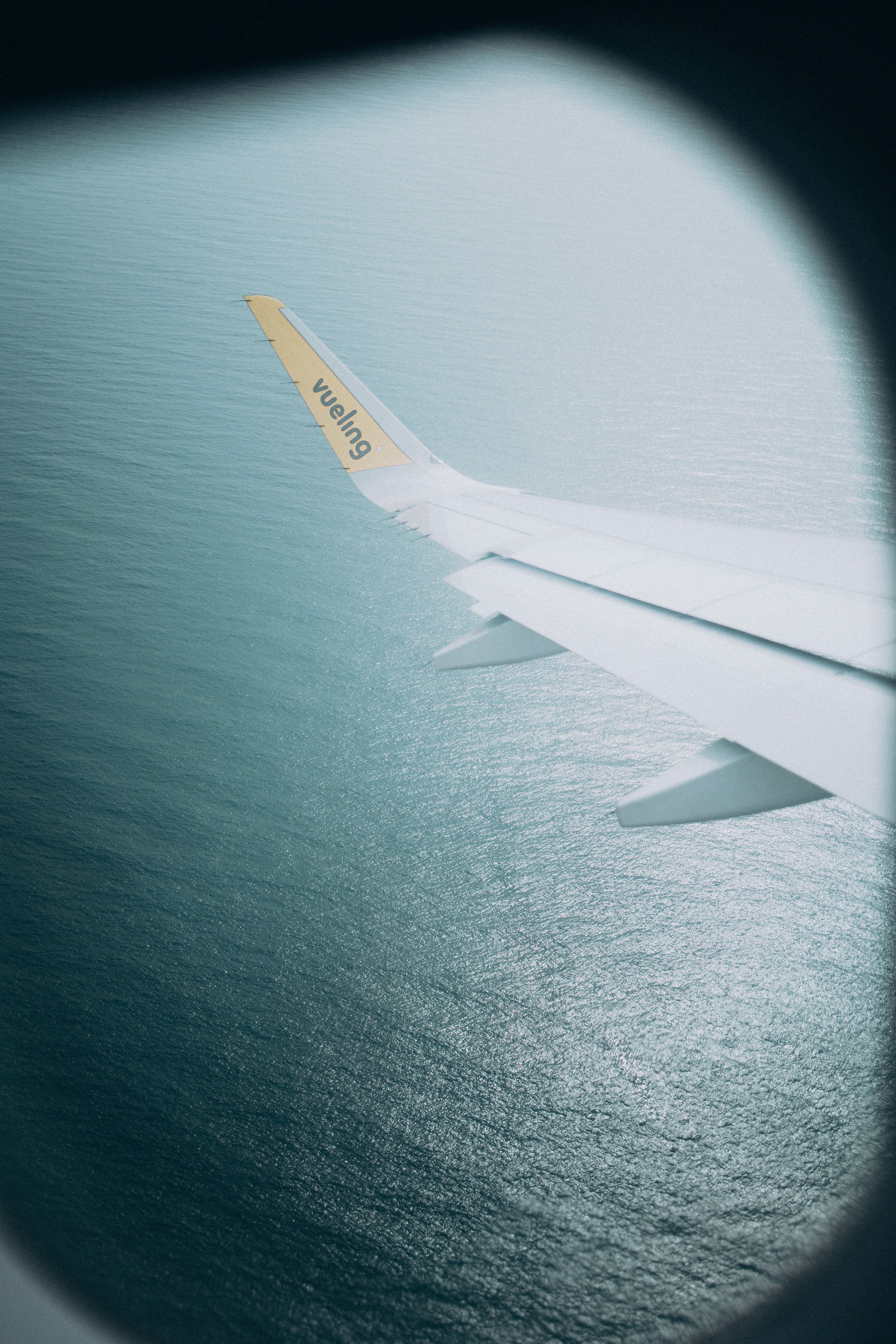 View of an airplane wing flying over the Mediterranean Sea near Barcelona.