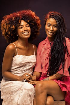 Two women share a joyful moment in a warm and stylish studio portrait.