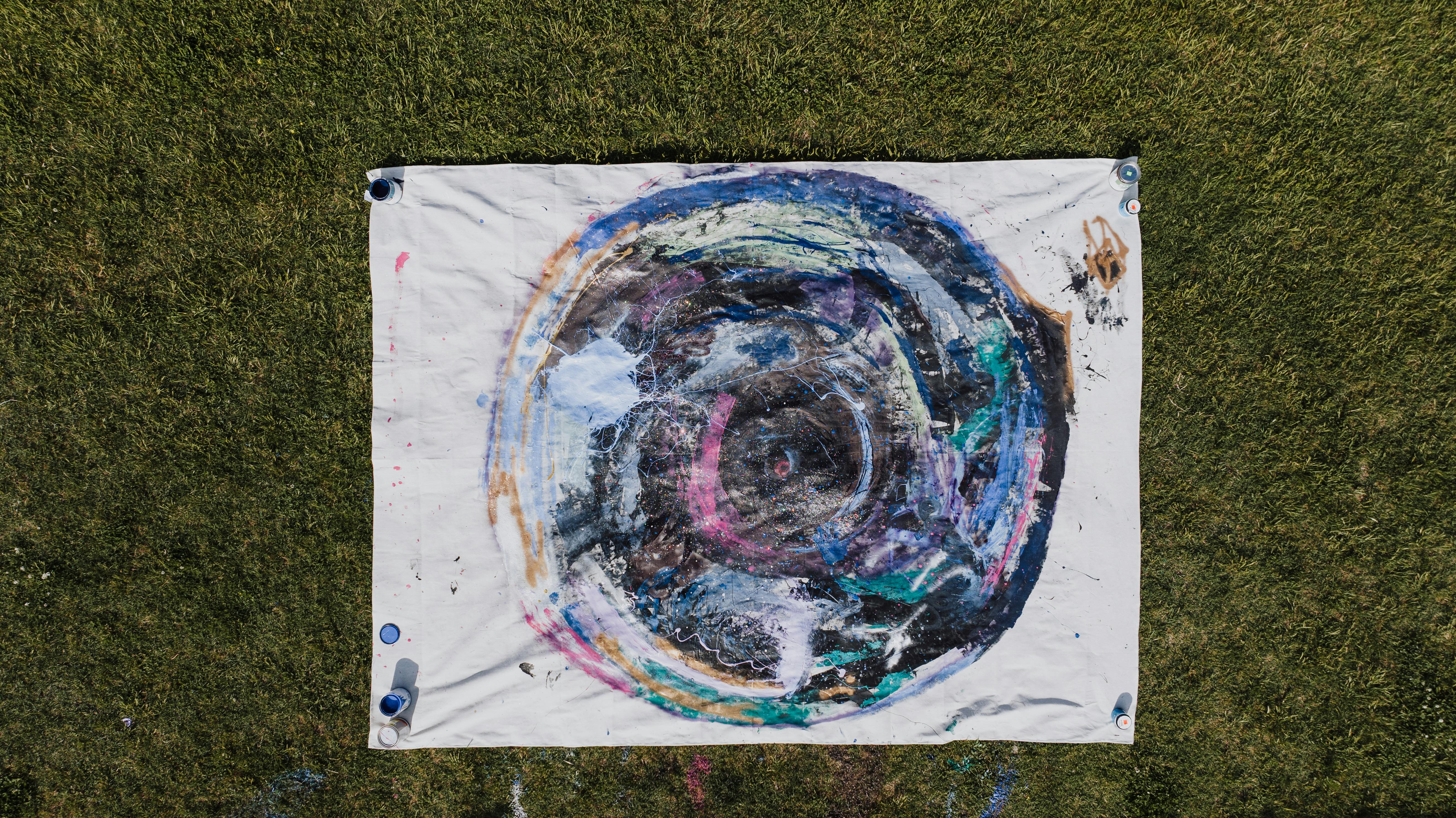 grátis Arte abstrata colorida em tela colocada na grama, exibindo uma criatividade vibrante de uma vista aérea. Foto profissional