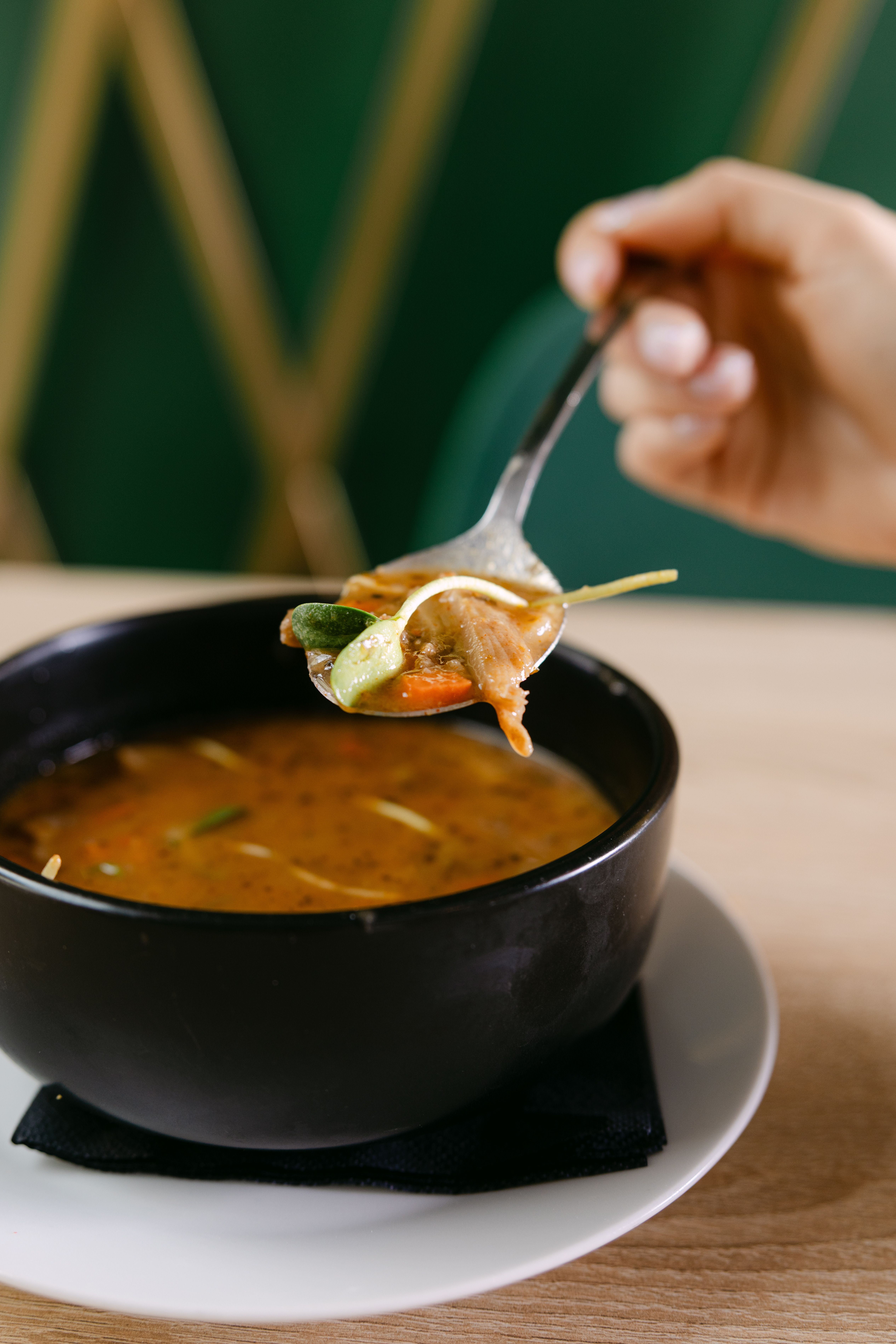 A spoon lifts vegetable soup from a bowl, showcasing a hearty meal.