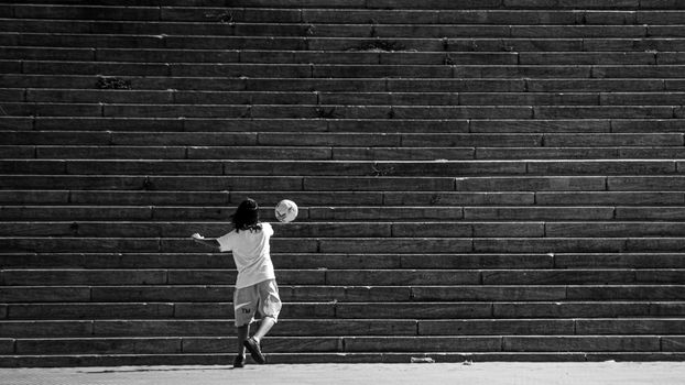 A child plays with a soccer ball against urban steps in Mar del Plata, Argentina.