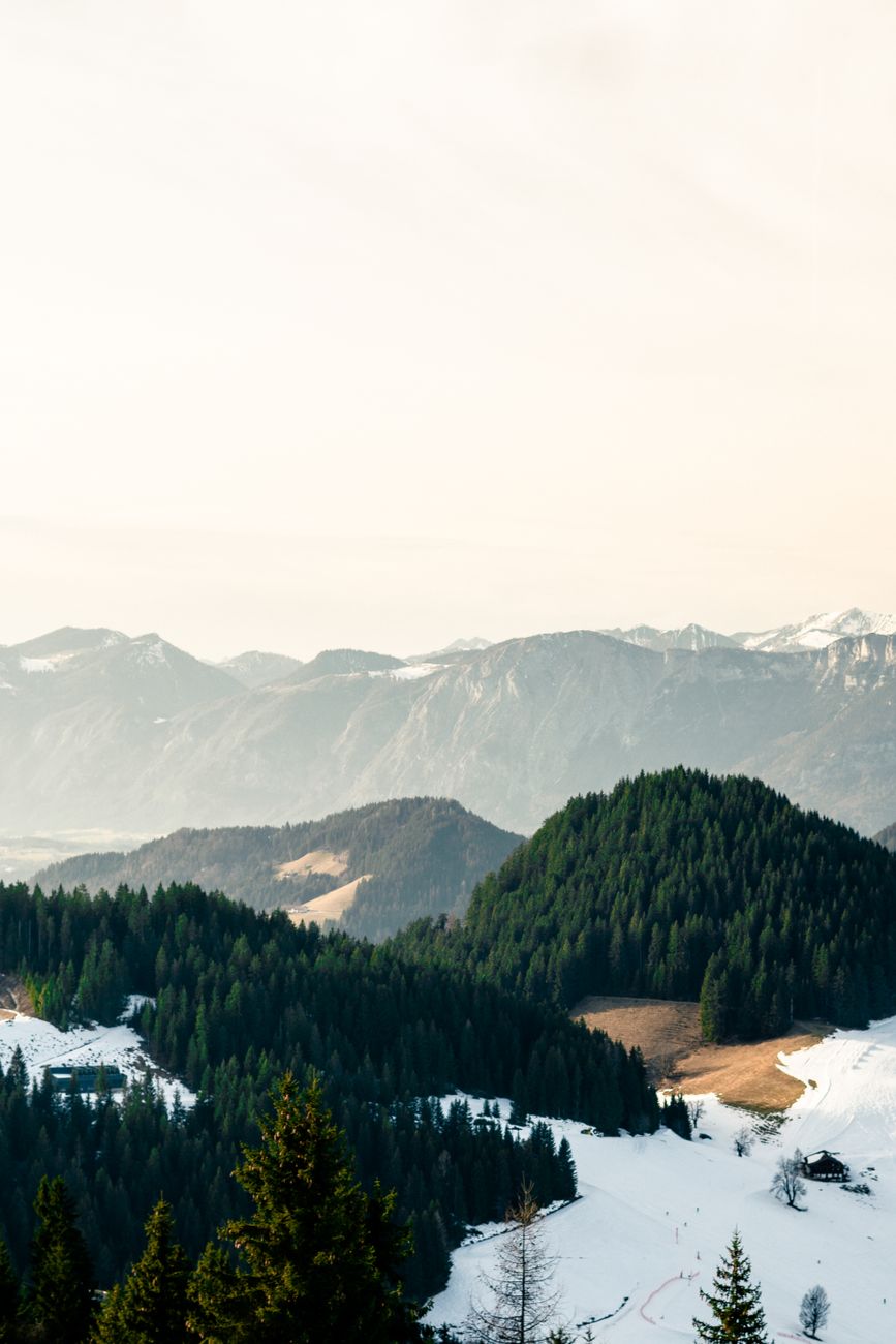 Breathtaking view of a tranquil alpine landscape with snow-covered mountains and lush forests.