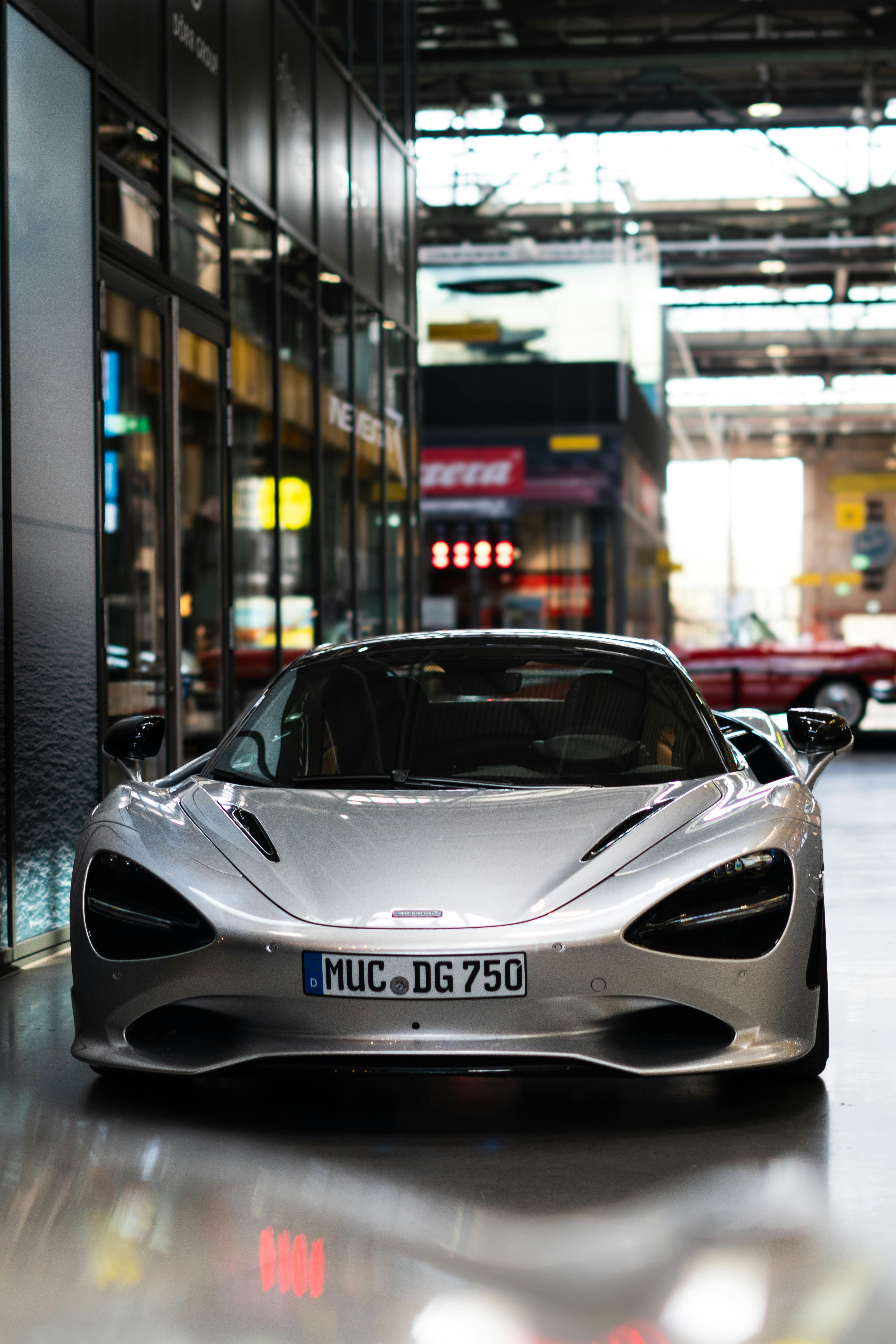 A stylish silver supercar parked indoors in a modern urban environment, showcasing sophistication.