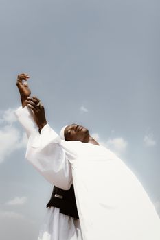 A person embracing the sky in Nigeria with elegant white clothing, capturing freedom and serenity.