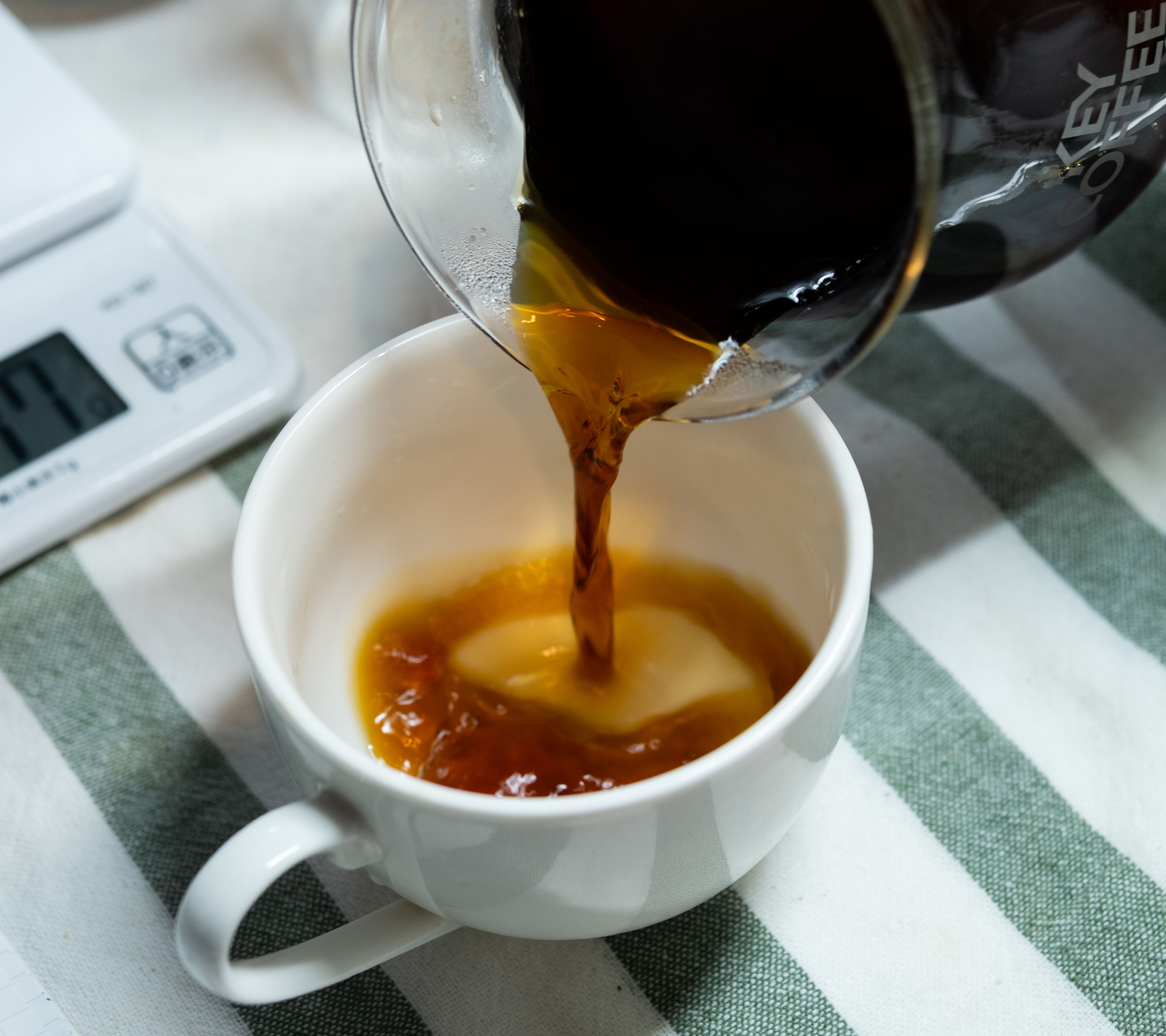 Close-up of freshly brewed coffee being poured into a white cup, creating a vibrant swirl.