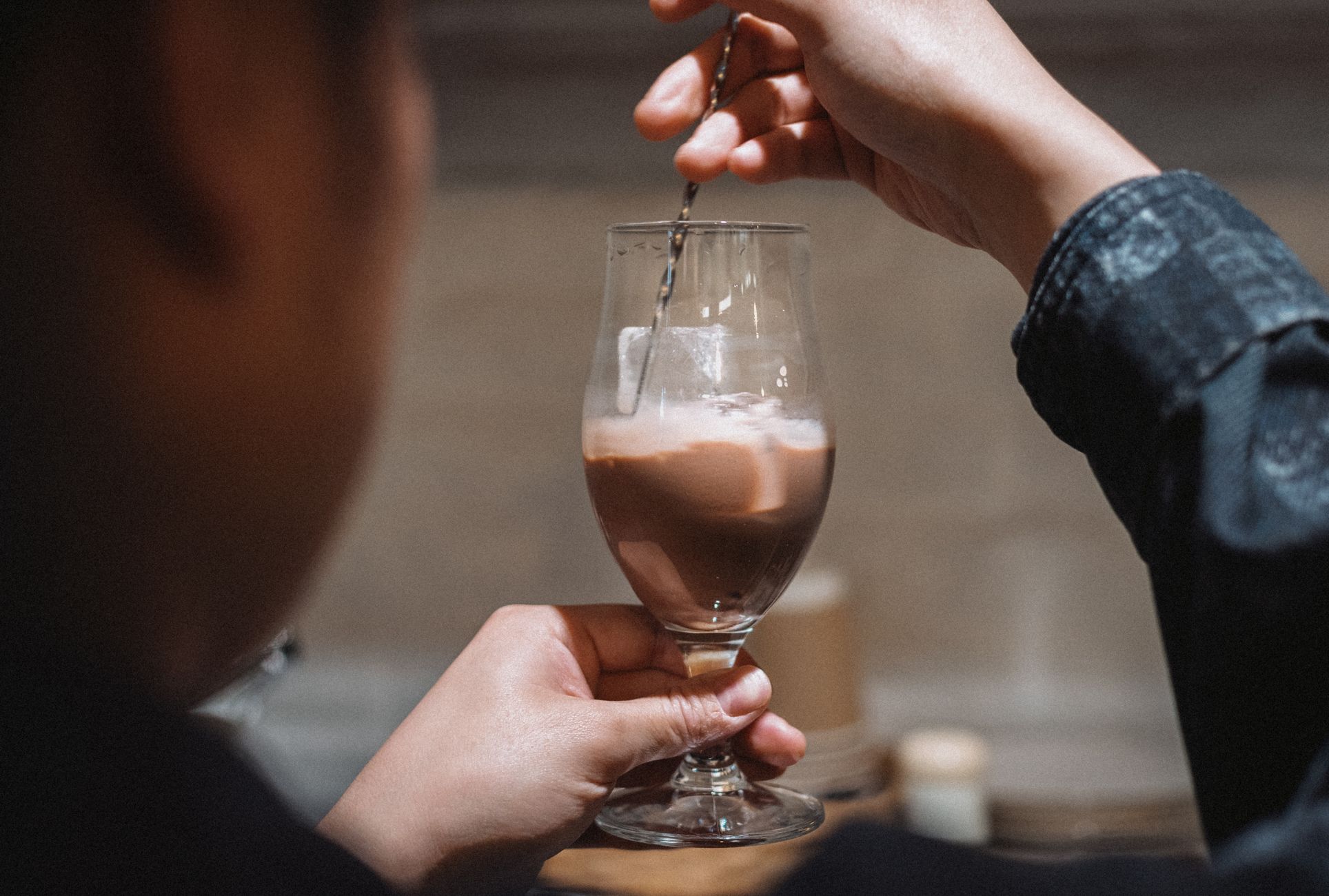 Barista stirring a creamy chocolate drink in a modern Tokyo cafe setting.
