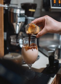 Close-up of a barista pouring espresso into an iced coffee at a Tokyo cafe.