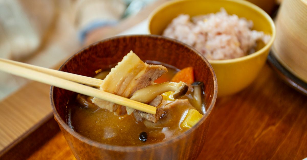 close-up of a jar of miso paste with a wooden spoon, steam rising from a bowl of soup