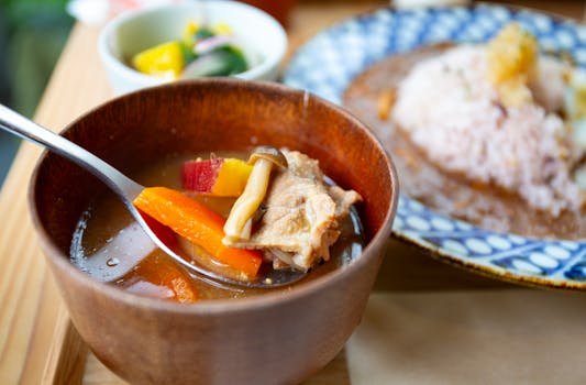 Delicious Japanese dish featuring soup with vegetables and curry rice, served in a cozy setting.