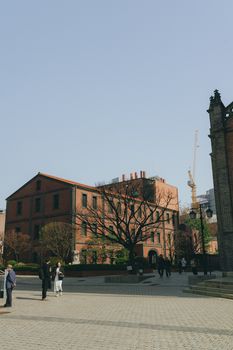 People walking by historic red brick buildings in downtown Seoul, showcasing city life.