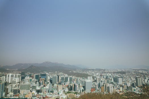 Panoramic view of Seoul's skyline against a mountainous backdrop, showcasing urban landscape.
