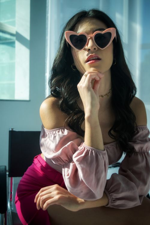 Free Stylish woman wearing heart-shaped sunglasses in an indoor setting, exuding modern fashion vibes. Stock Photo