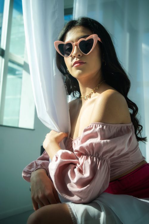 Free Elegant woman with heart-shaped sunglasses posing in sunlight, showcasing fashion and confidence. Stock Photo