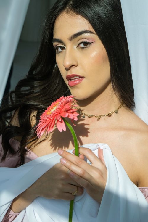 Free Elegant portrait of a woman with a pink gerbera daisy, showcasing beauty and grace. Stock Photo