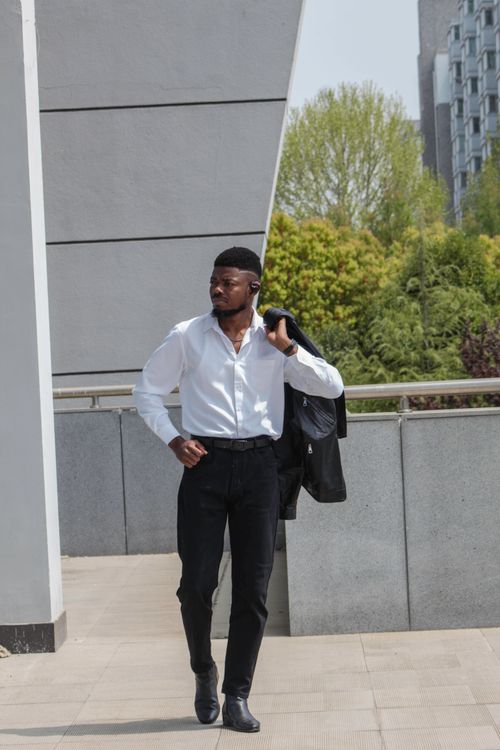 Free A man in formal attire confidently walking in an urban outdoor environment. Stock Photo