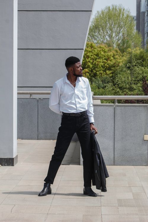Free Young man in chic attire posing outdoors combining style and elegance. Stock Photo
