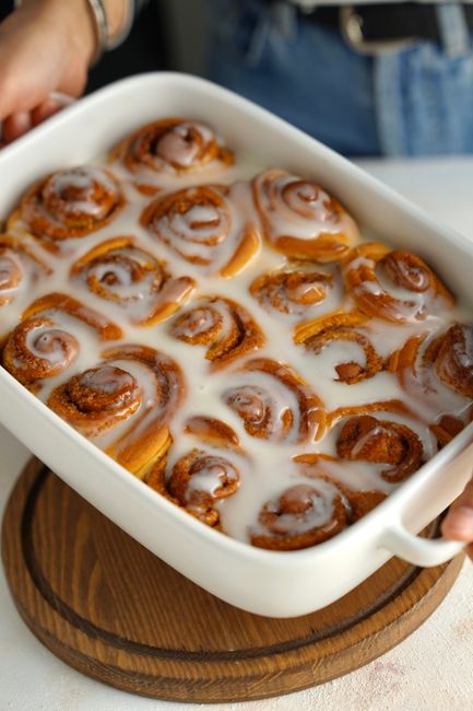 Freshly baked cinnamon rolls with creamy icing in a baking dish.