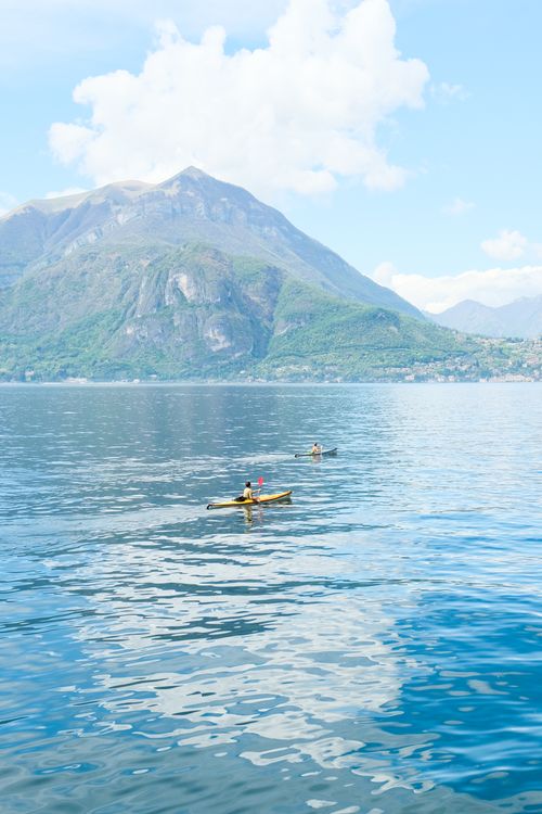 Free Two kayakers paddle on the serene waters of Lake Como beneath a stunning mountain backdrop in Lombardy, Italy. Stock Photo