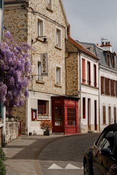 Picturesque view of a quaint Parisian street corner adorned with blooming wisteria and classic stone buildings.