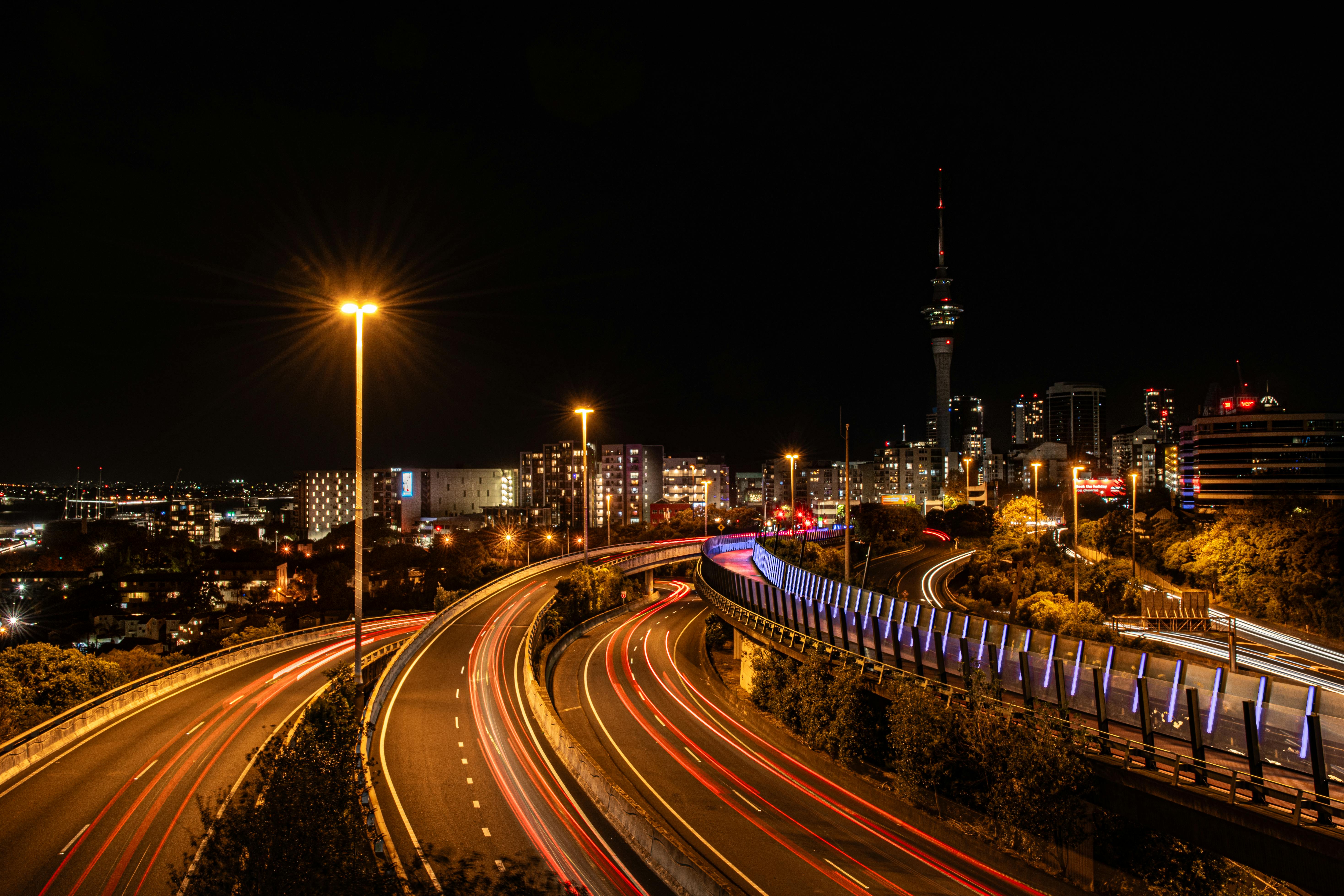Stunning night view of Auckland's skyline with dynamic light trails on city highways.