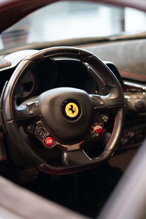 Free Close-up view of a Ferrari steering wheel inside a luxury supercar, highlighting design and craftsmanship. Stock Photo