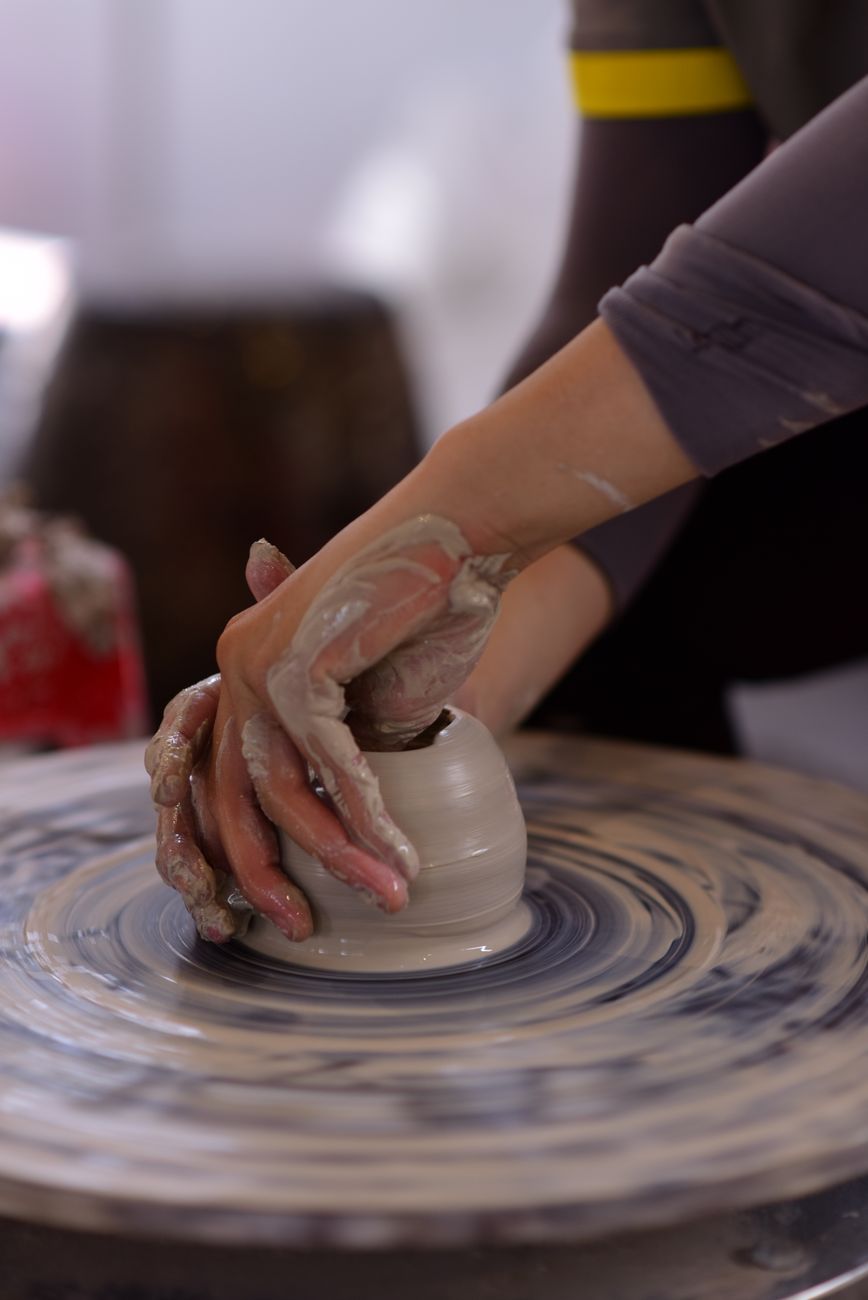 Hands crafting a clay pot on a pottery wheel, showcasing traditional handmade techniques.