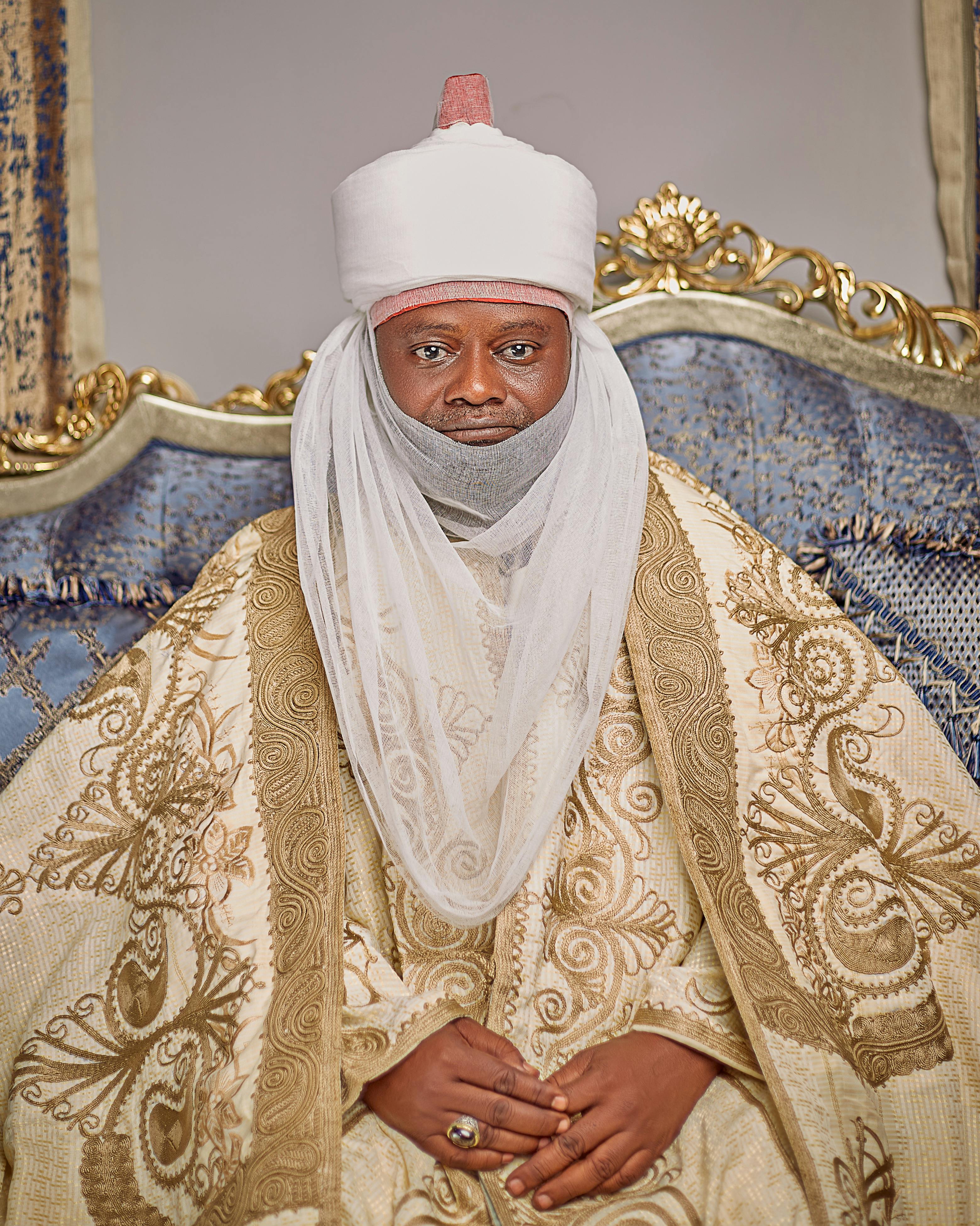 Portrait of an African chief wearing ornate traditional attire and headgear.