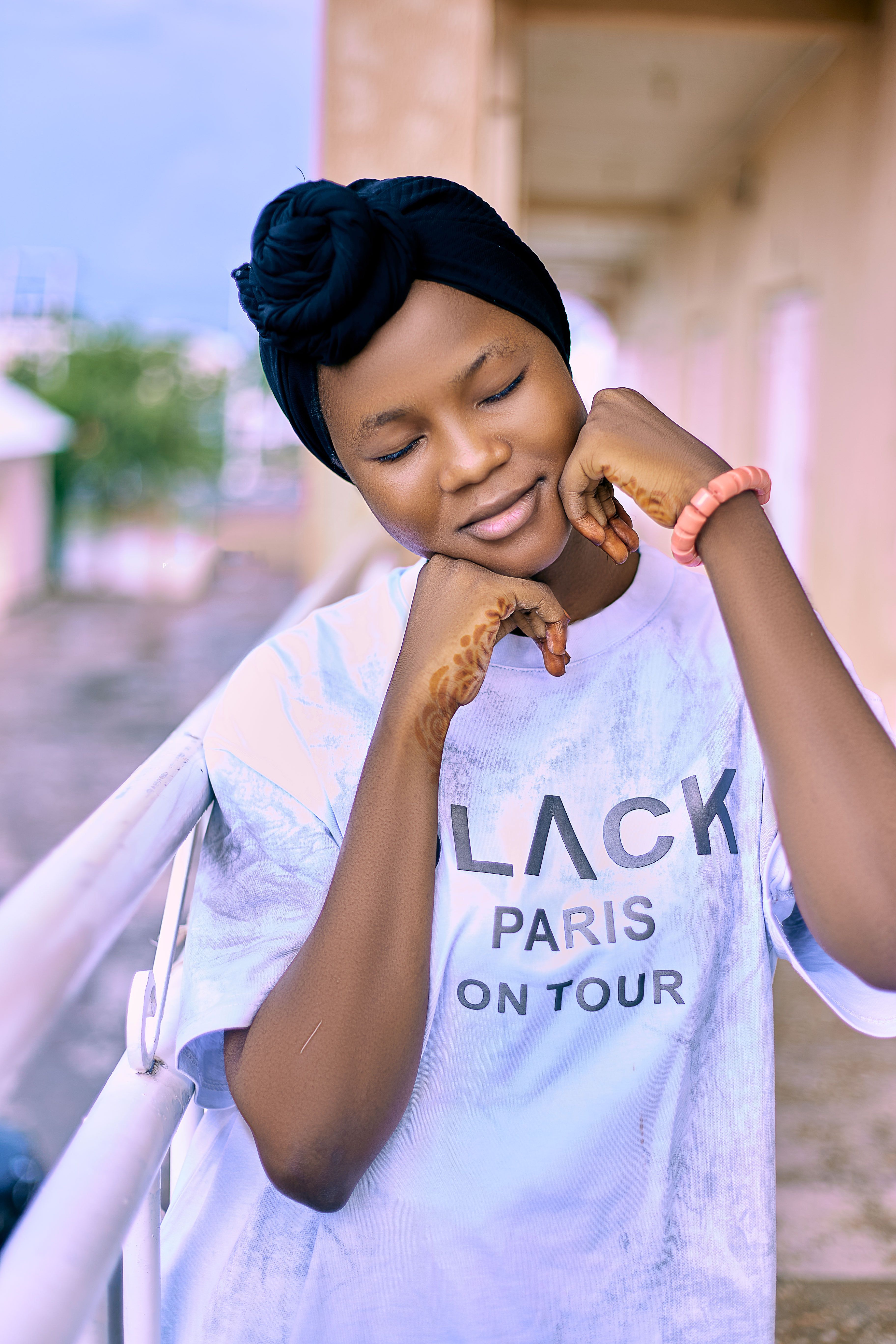 Smiling young woman posing with closed eyes outdoors in fashionable t-shirt.