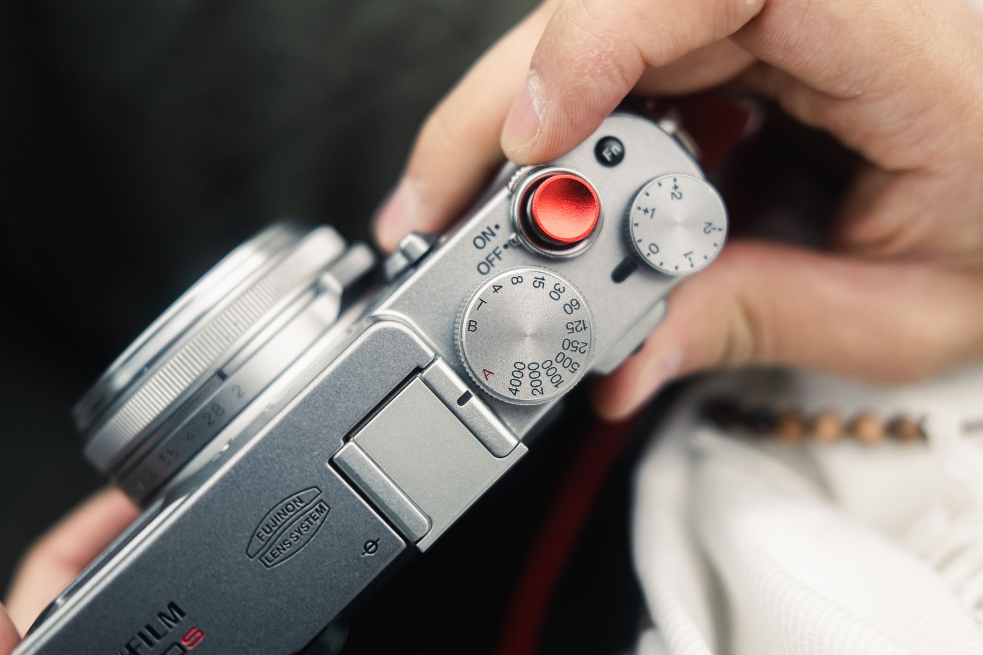 A detailed view of a hand adjusting a camera dial, focusing on the settings and design.