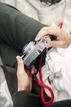 A detailed view of a person holding a compact camera, capturing creative photography moments.