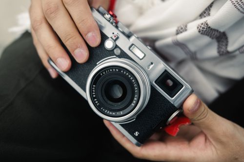 Free A detailed close-up view of a person holding a Fujifilm camera, emphasizing the intricate design. Stock Photo