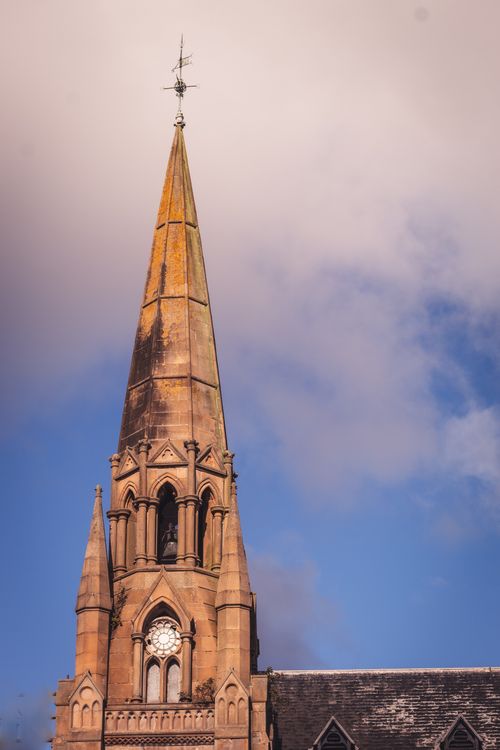 Free Gothic church spire reaching into a clear blue sky, capturing architectural elegance. Stock Photo