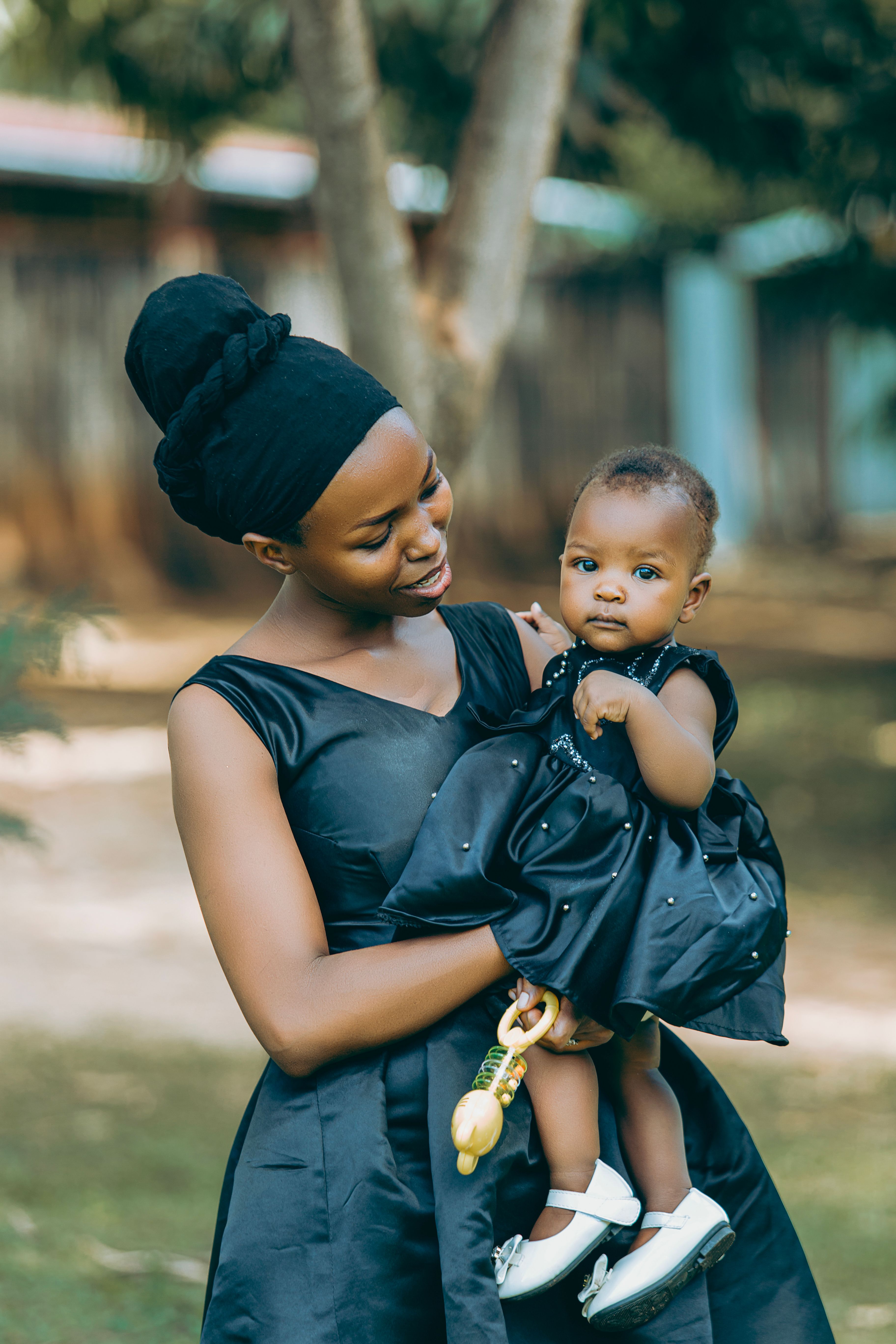 Mother Holding Her Baby Outdoors in Elegant Black  Free Stock Photo