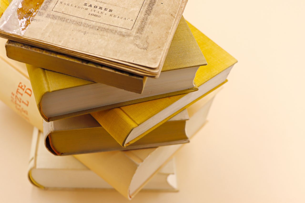a collection of antique books stacked on a warm cream background showc