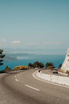 Curved highway with cars driving along a picturesque ocean view on a sunny day.