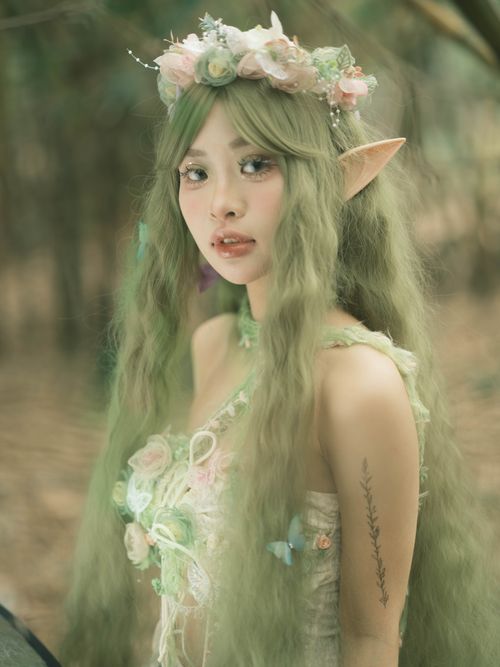 Free A young woman dressed as an elf stands in a lush forest, evoking a mystical fantasy world. Stock Photo